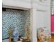 Detailed view of a fireplace with patterned wallpaper, stylish accessories, and classic checkerboard tile accents at 8 Desoto E St, Bradenton, FL 34208