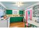 Eat-in kitchen featuring bright green cabinetry, unique wallpaper, hardwood floors, and stainless steel appliances at 8 Desoto E St, Bradenton, FL 34208