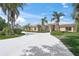 Sprawling ranch-style home with a circular driveway and lush tropical landscaping at 8 Dominica Dr, Englewood, FL 34223