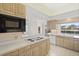 Kitchen with wood cabinets, white countertops, and tile floors with view to living area at 8 Dominica Dr, Englewood, FL 34223