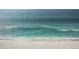 Aerial view of clear turquoise waves gently lapping against the white sand beach at 924 Indian Beach Dr, Sarasota, FL 34234
