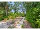 Lush backyard garden with winding stone pathway, vibrant flora, and serene foliage at 924 Indian Beach Dr, Sarasota, FL 34234