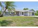 Inviting single-story home with a lush front yard, mature palm tree, attached garage, and a charming entryway with flower beds at 104 Hourglass Dr, Venice, FL 34293