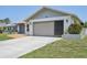 Home's facade featuring a concrete driveway leading to a large two-car garage and manicured flower beds at 104 Hourglass Dr, Venice, FL 34293