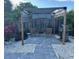 Outdoor seating area under a wooden pergola with shade covering, grill, and stone patio at 1204 Sunrise Rd, Venice, FL 34293