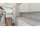 Hallway view of the kitchen, featuring bright white cabinets, a granite countertop and hardwood floors at 13115 Harriers Pl, Bradenton, FL 34212