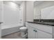 Well-lit bathroom with a white tiled tub-shower, gray granite vanity, and decorative turquoise knobs at 13915 Mount Laurel Trl, Bradenton, FL 34211