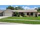 Well-maintained single-story home boasts a manicured lawn, mature landscaping, and an attached two-car garage at 1612 Shady Leaf Dr, Valrico, FL 33596