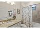 Well-maintained bathroom with tiled shower featuring marble-themed shower curtain and granite countertops at 17728 Polo Trail, Lakewood Ranch, FL 34211