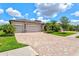 Beautiful home with a brick driveway and a three-car garage is surrounded by lush landscaping at 17728 Polo Trail, Lakewood Ranch, FL 34211
