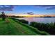 Picturesque lake view showcasing a peaceful waterfront setting and community homes with lights at 17728 Polo Trail, Lakewood Ranch, FL 34211