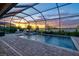 Screened-in pool with pavers offers a gorgeous view of the sunset on the lake at 17728 Polo Trail, Lakewood Ranch, FL 34211