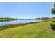 Picturesque view of a tranquil lake surrounded by lush greenery and well-manicured lawn at 23528 Awabuki Dr # 101, Venice, FL 34293