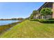 Lush backyard bordering a serene lake, featuring well-maintained landscaping and mature trees at 23528 Awabuki Dr # 101, Venice, FL 34293