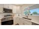 Modern kitchen with stainless steel appliances, quartz countertops, and white cabinets by the window at 2825 Pinecrest St, Sarasota, FL 34239