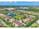 Expansive aerial view of a townhouse community with a central pond, surrounded by lush greenery and other residences at 3760 82Nd Avenue E Cir # 102, Sarasota, FL 34243