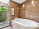 Relaxing bathroom with a soaking tub and tropical garden views from the glass-enclosed shower at 3905 Country View Dr, Sarasota, FL 34233