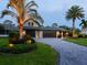 Beautiful home with lush landscaping, featuring a paved driveway and a well-manicured lawn with mature palm trees at 3905 Country View Dr, Sarasota, FL 34233