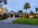 Charming home with lush landscaping, featuring a paved driveway and a well-manicured lawn with mature palm trees at 3905 Country View Dr, Sarasota, FL 34233