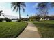Sidewalk view leading towards a tranquil lake featuring lush landscaping and a charming gazebo at 3919 Glen Oaks Manor Dr, Sarasota, FL 34232