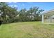 Large grassy backyard with mature trees and a black fence at 4015 Quiet Rain Ct, Palmetto, FL 34221