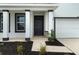 Inviting two-story home entrance featuring dark trim, two-car garage, a covered porch, and fresh landscaping at 4015 Quiet Rain Ct, Palmetto, FL 34221