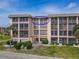 A welcoming condo exterior featuring screened balconies, well-kept lawns, and colorful tropical landscaping at 4189 Heron Way # 406E, Bradenton, FL 34205
