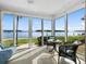Bright sunroom with panoramic water views, wicker furniture, and a ceiling fan for optimal comfort at 4310 Falmouth Dr # 105, Longboat Key, FL 34228
