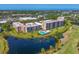 Aerial view of condos, a community pool, and a scenic pond in a lush, landscaped environment at 4550 Pinebrook Cir # 608, Bradenton, FL 34209