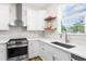 Well-lit kitchen with stainless steel appliances, white cabinets, floating shelves, and modern backsplash at 4718 Arbor Gate Dr, Bradenton, FL 34203