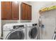 Convenient laundry room with modern washer and dryer, dark wood cabinets, and organized shelving at 4718 Arbor Gate Dr, Bradenton, FL 34203