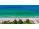 Breathtaking aerial view of the sandy beach, calm turquoise waters, and colorful umbrellas at 4840 Gulf Of Mexico Dr # Villa 15, Longboat Key, FL 34228