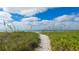 Scenic beach path surrounded by verdant foliage with a view of the clear blue ocean and bright sky at 4840 Gulf Of Mexico Dr # Villa 15, Longboat Key, FL 34228
