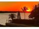 Waterfront view of a scenic sunset with palm trees silhouetted against the orange sky, by a private dock at 4840 Gulf Of Mexico Dr # Villa 15, Longboat Key, FL 34228