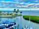 Scenic waterfront view with boat docks and lush tropical landscaping under a cloudy blue sky at 4840 Gulf Of Mexico Dr # Villa 15, Longboat Key, FL 34228