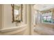 Elegant bathroom hallway with wall mirror, shelf and plant leading to a luxurious tub at 4920 Woodhurst Dr, Sarasota, FL 34243
