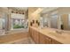 Bright bathroom boasts dual sinks, large mirror, soaking tub and outdoor views at 4920 Woodhurst Dr, Sarasota, FL 34243