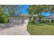Charming single-story home with a well-manicured lawn, mature trees, and a brick driveway at 4920 Woodhurst Dr, Sarasota, FL 34243