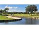 Picturesque golf course with water features, a bridge, sand trap, and palm trees at 4920 Woodhurst Dr, Sarasota, FL 34243