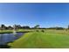 Picturesque golf course view featuring a pond with fountain, palm trees, and well-manicured green grass at 4920 Woodhurst Dr, Sarasota, FL 34243