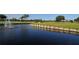 Scenic view of a pond with a fountain, green grass, and a wooden retaining wall at 4920 Woodhurst Dr, Sarasota, FL 34243