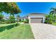 Single-story home showcasing a well-maintained lawn, paver driveway, and neutral colored two-car garage at 5035 Tobermory Way, Bradenton, FL 34211