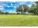 Expansive view of a pristine golf course with mature trees, a serene pond, and a clear blue sky at 5035 Tobermory Way, Bradenton, FL 34211
