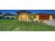 Exterior elevation of the home with manicured lawn and tropical landscaping at 5500 Merrimac Dr, Sarasota, FL 34231