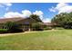 Exterior shot of Longboat Key Education Center. Single story building with front lawn and mature trees under blue sky at 5626 Pipers Waite # 22, Sarasota, FL 34235