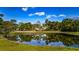 Scenic pond reflecting the golf course landscape, surrounded by green grass and mature trees on a clear day at 5626 Pipers Waite # 22, Sarasota, FL 34235