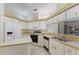 Bright kitchen with white appliances, white cabinets, and a view through to the sunroom at 5712 Garden Lakes Dr, Bradenton, FL 34203