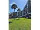 Exterior shot of a white condo building with palm trees and well-maintained lawn at 5855 Midnight Pass Rd # 621, Sarasota, FL 34242