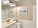 Bright bathroom features a white vanity, neutral walls, and stylish beach-themed artwork at 5877 Ferrara Dr, Sarasota, FL 34238