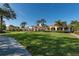 A beautiful exterior elevation with a large manicured lawn, mature palm trees, and a bright blue sky at 5877 Ferrara Dr, Sarasota, FL 34238
